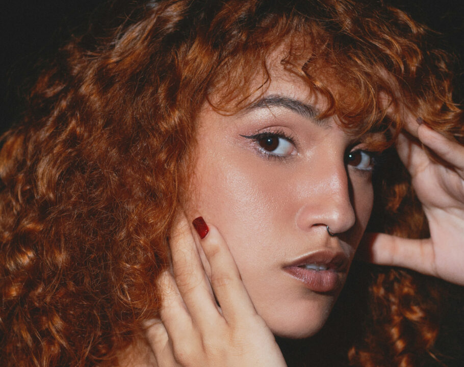 Photo of woman with curly red hair against black background