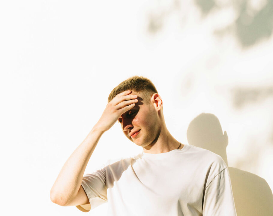 Man in sunlight with hand on his forehead
